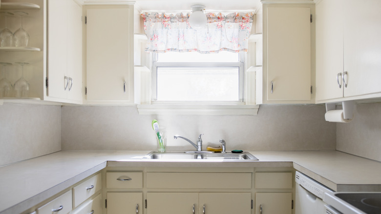 A sunny white and beige kitchen with off-white standard overlay kitchen cabinets