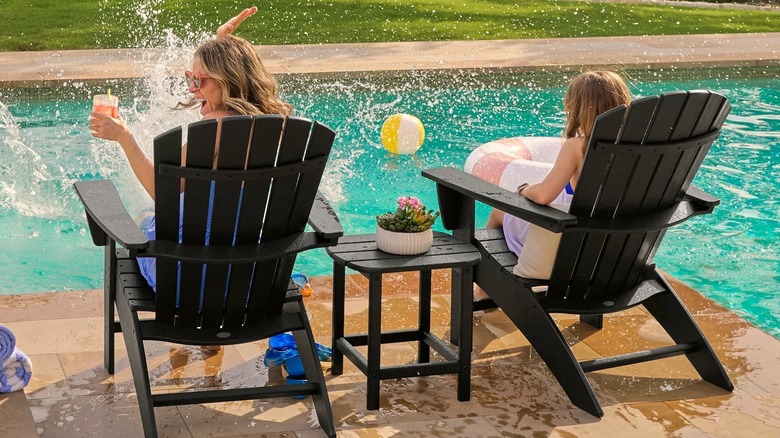 People sitting in Adirondack chairs near an outdoor pool
