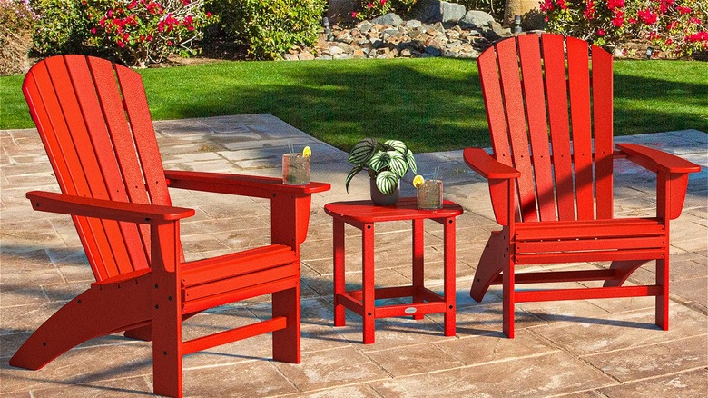 Two red Adirondack chairs with drinks and a plant