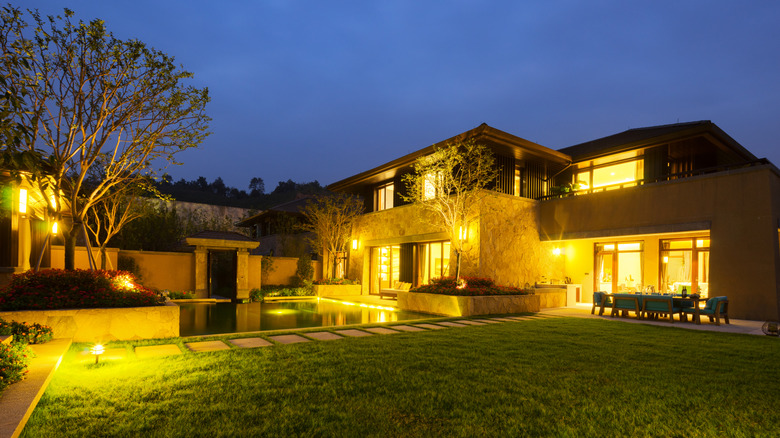 backyard stone house exterior illuminated with landscape lighting