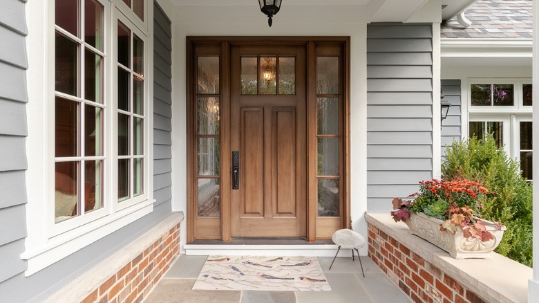 A house exterior with a wooden ornate door and grey siding.
