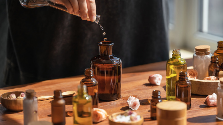 Hands transferring essential oil into a bottle on a wooden table
