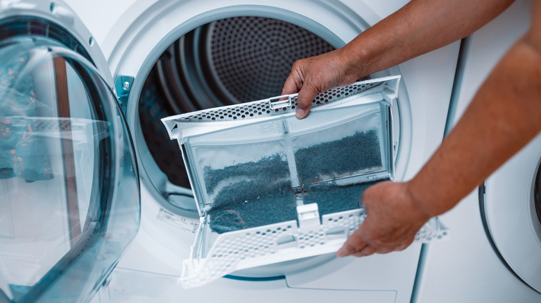 Person cleaning the lint trap in a dryer