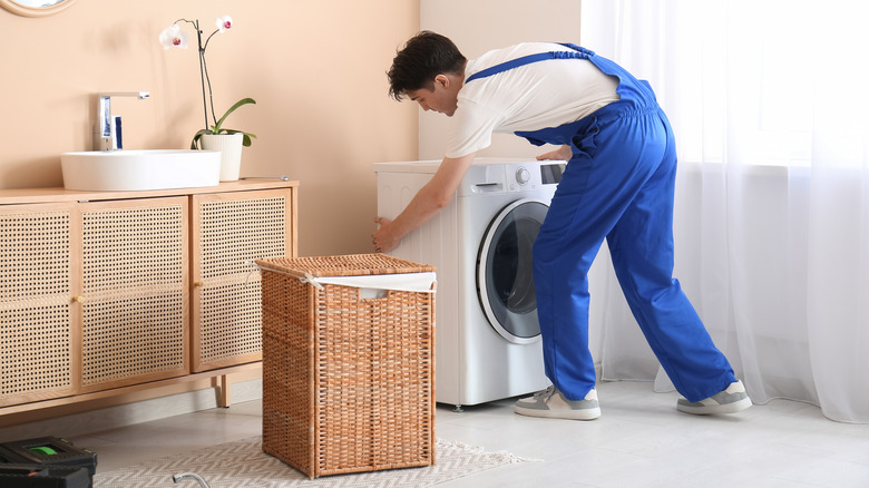 Person sliding a washing machine out from its spot