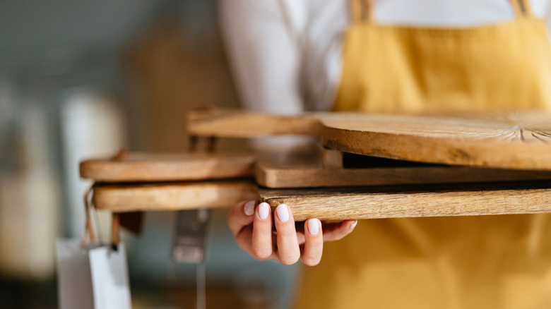 Woman holding a stack of wooden cutting boards.