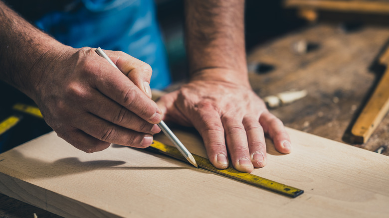 Someone measuring wood before cutting
