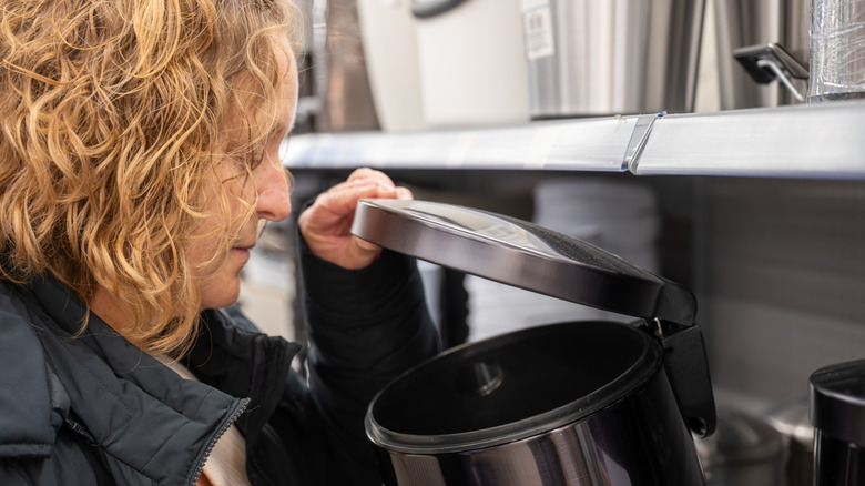 Woman examining a metal trash can