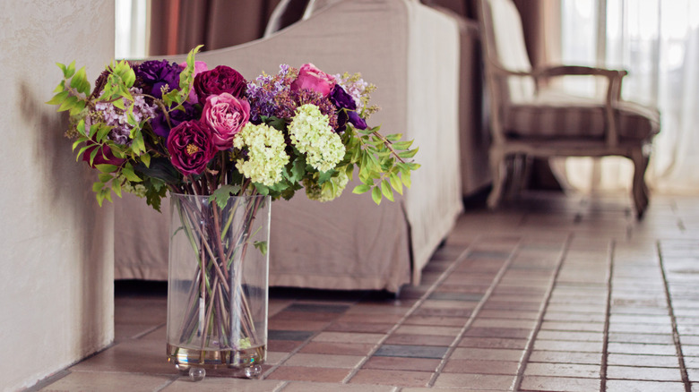 A bouquet of faux flowers sits on a tile floor