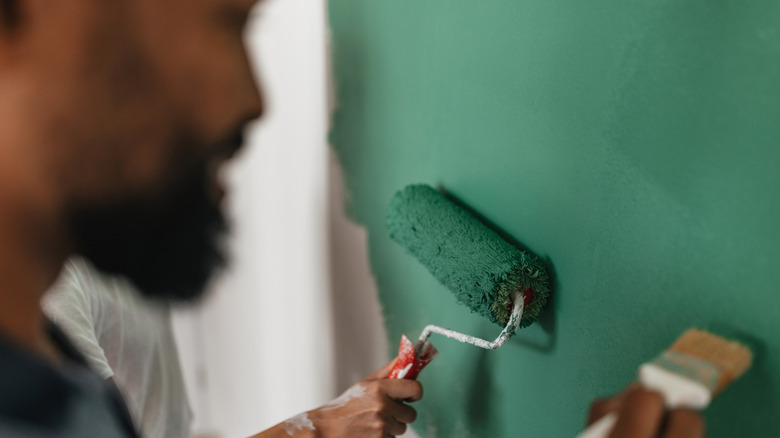 A couple paints a wall a vibrant kelly green.