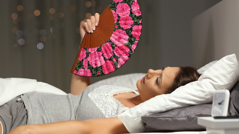 Person fanning themselves in bed