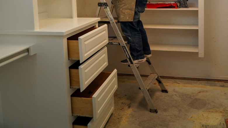 A woman painting the shelves inside a closet.