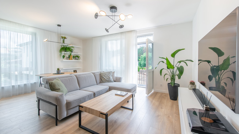 Modern living room with white walls, ceiling, and curtains and a grey couch