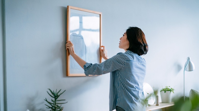 Woman hanging up wall art