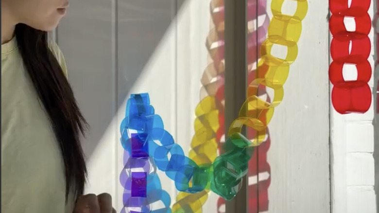 Woman standing next to a window with a suncatcher made of light-filtering paper hanging in front of the glass