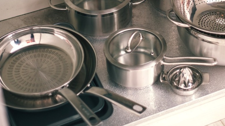 stainless steel pots and pans stacked under kitchen sink