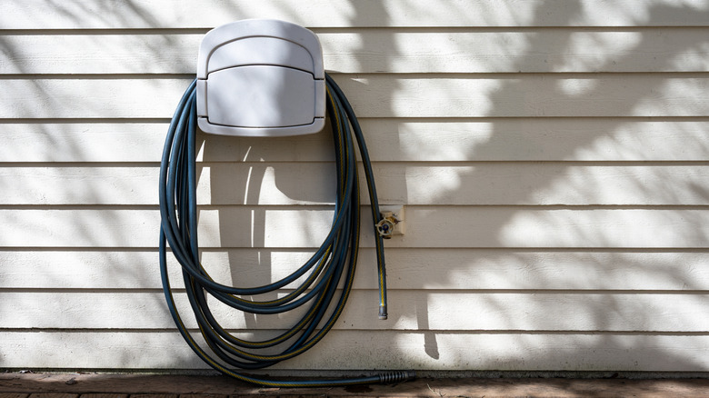 A garden hose coiled on a wall mounted hanger