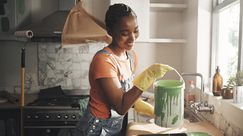 woman pouring paint in kitchen