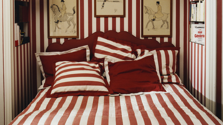 Red and white stripe pattern drenching in a bedroom, including the wallpaper and bed linen