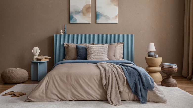 bedroom with blue headboard and abstract art on walls
