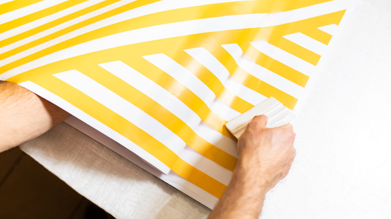 A person rolling out peel and stick wallpaper.