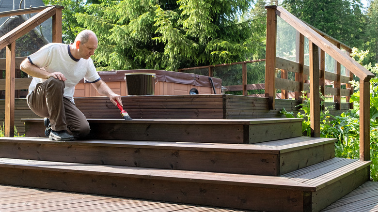 man sealing wood deck stairs