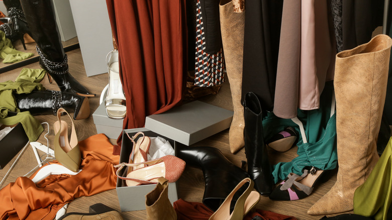 A messy closet with shoes and clothes on the floor