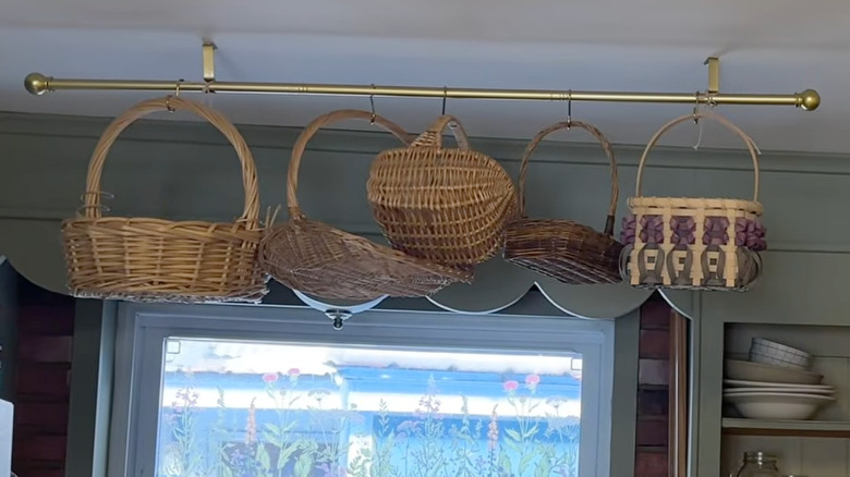 Thrifted baskets hung up on a gold curtain rod above a kitchen window