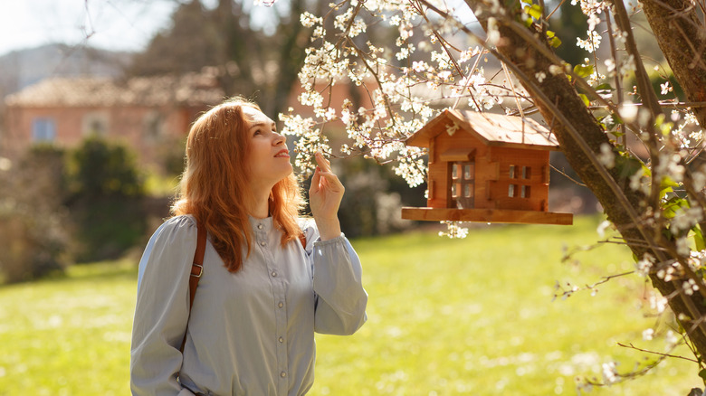 woman looking at flowers surrounding bird feeder