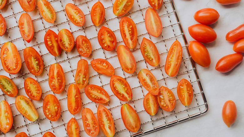 Sliced cherry tomatoes on an oven rack.