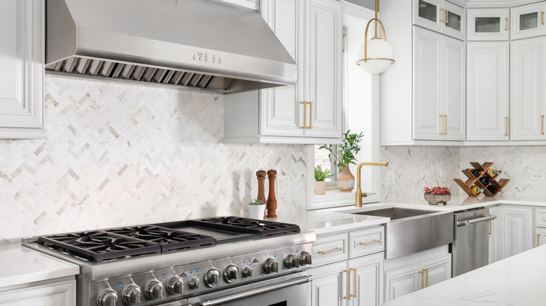 Modern white kitchen with marble backsplash and stainless steel appliances