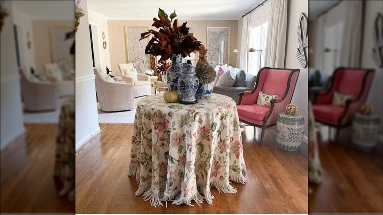 A decorator table with floral cloth and decor on top.