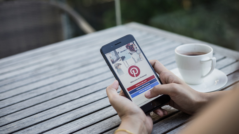 A woman holding a phone with the Pinterest app open