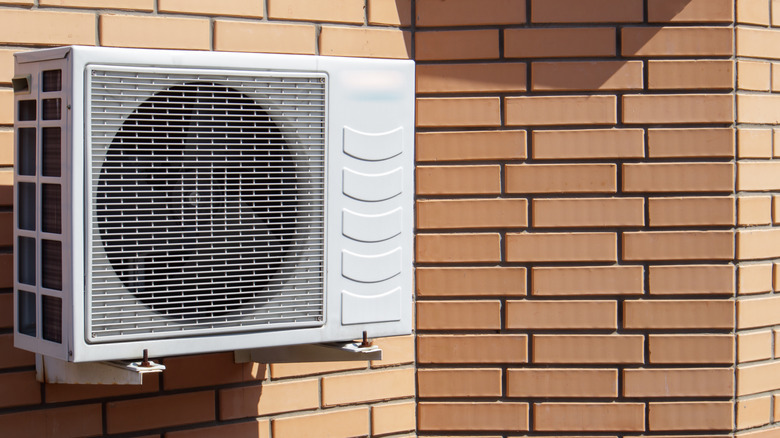 Close-up shot of a modern climate control unit against the background of a brick wall of the facade of a house outside
