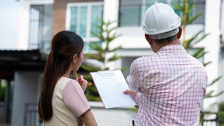 Home inspector in hard hat speaking to a homeowner.