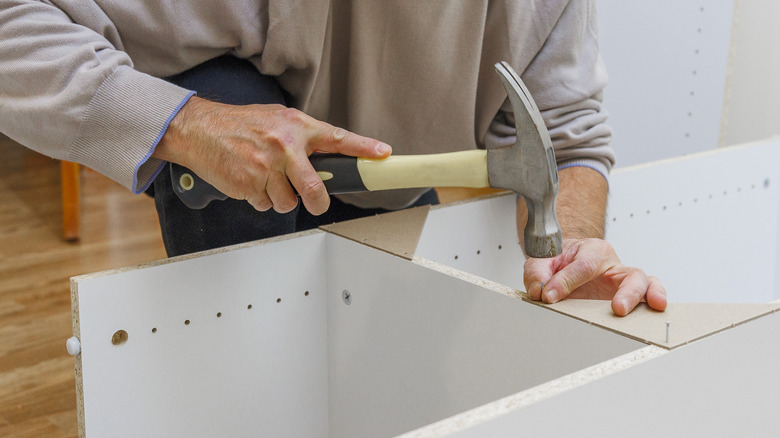 Person hammering nail into shelf