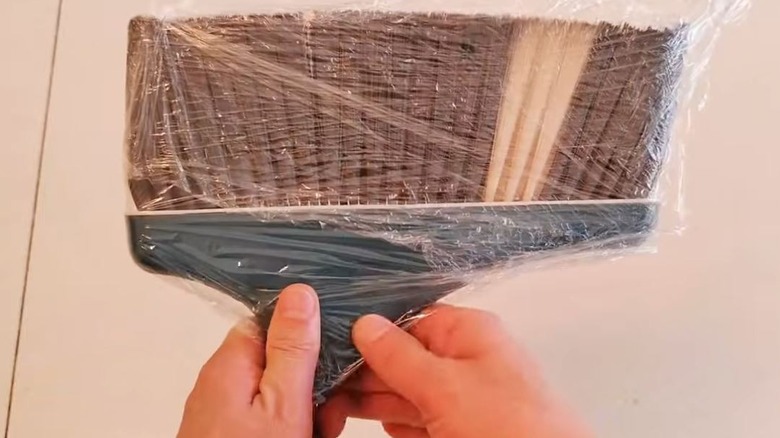 Man wrapping broom with plastic wrap for hack