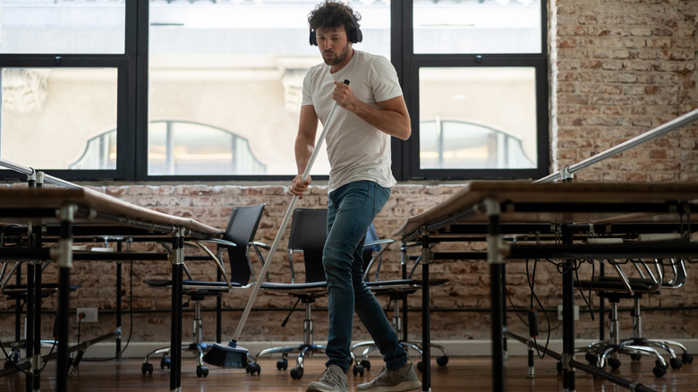 Man sweeping with broom with headphones