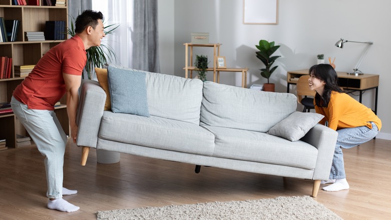 man and woman moving sofa