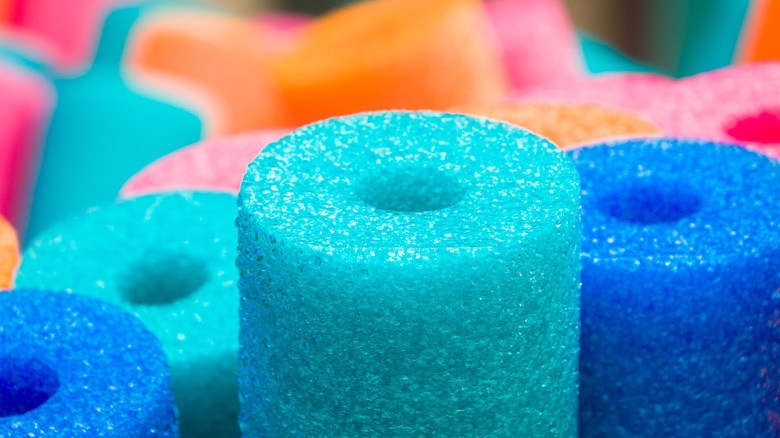 Blue, teal, orange and pink pool noodles up close