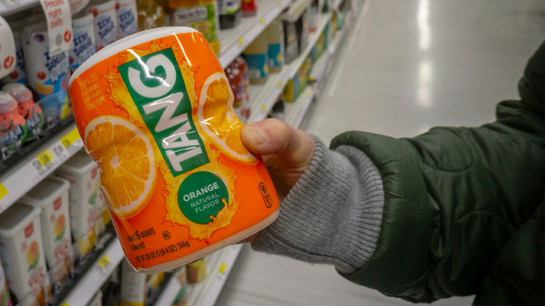 A person holding container of Tang in a grocery aisle