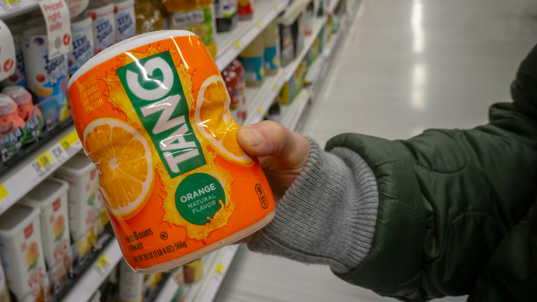 A person holding container of Tang in a grocery aisle