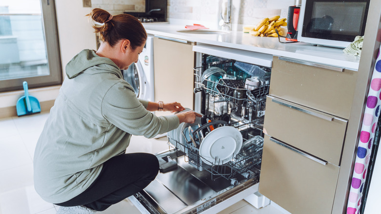 A woman emptying dishwasher full of dishes