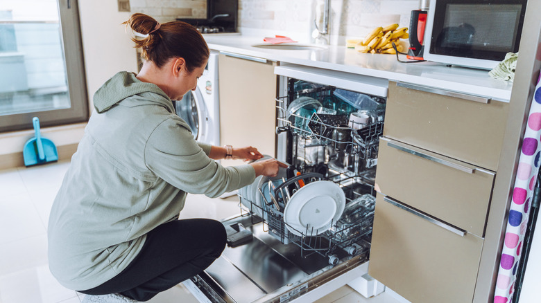 A woman emptying dishwasher full of dishes