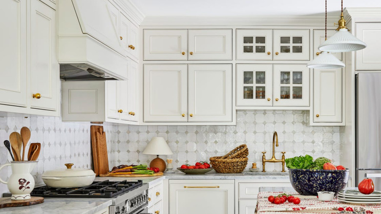 A bright, white modern kitchen with brass hardware, faucet, and cabinet pulls.