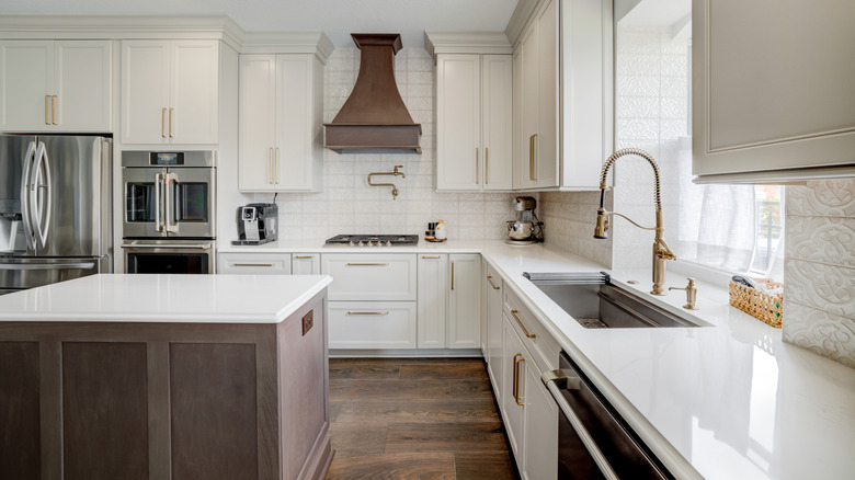 A spacious white kitchen with gold and dark wood accents