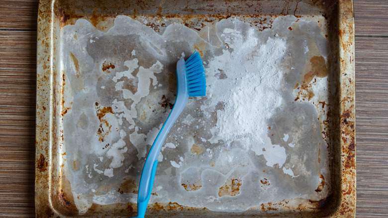 A dirty baking sheet covered in a cleaning powder.