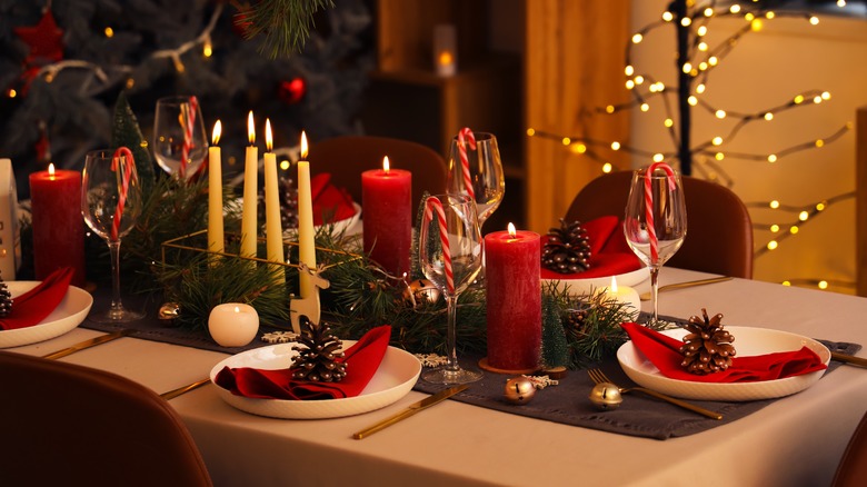 A festive table set with holiday decorations and tall candles.