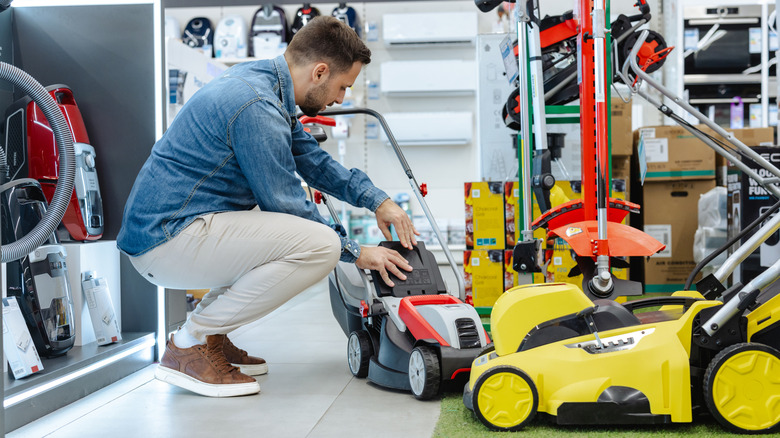 A man shopping for a lawn mower in a store