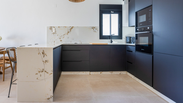 an open-concept kitchen with dark cabinets and large format tile floors