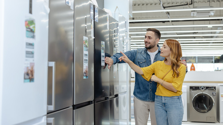 two people shopping for a refrigerator in an appliance store